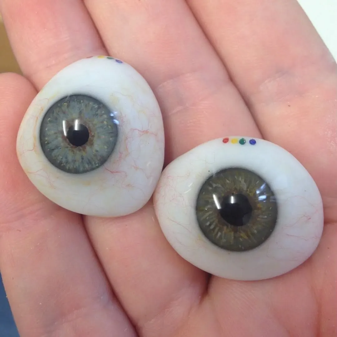 Selection of prosthetic eyes in a range of iris colours from soft hazel to vivid blue, each meticulously colour-matched for its wearer