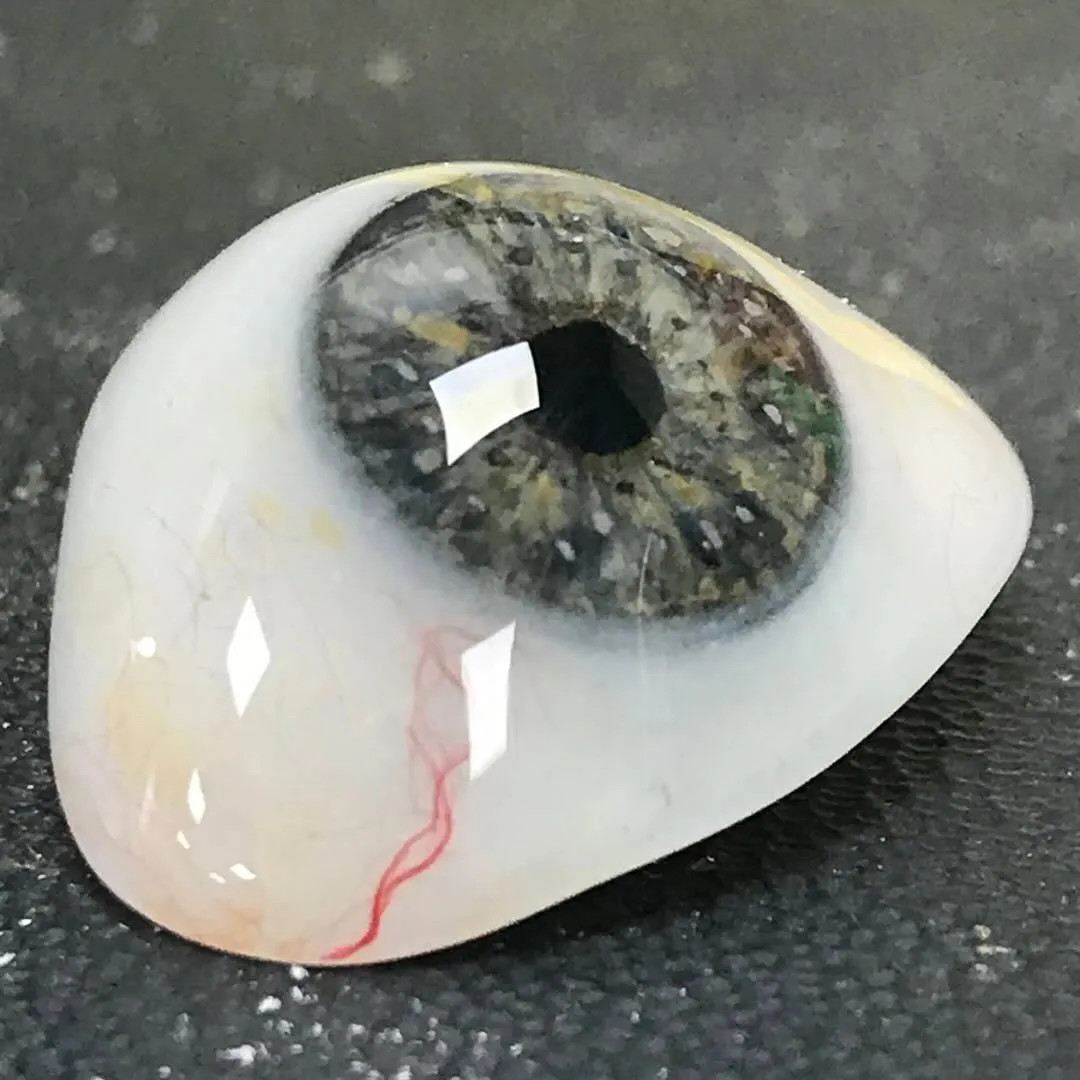 Detailed view of a prosthetic eye featuring delicate scleral veins and subtle imperfections that mirror the natural character of a real eye